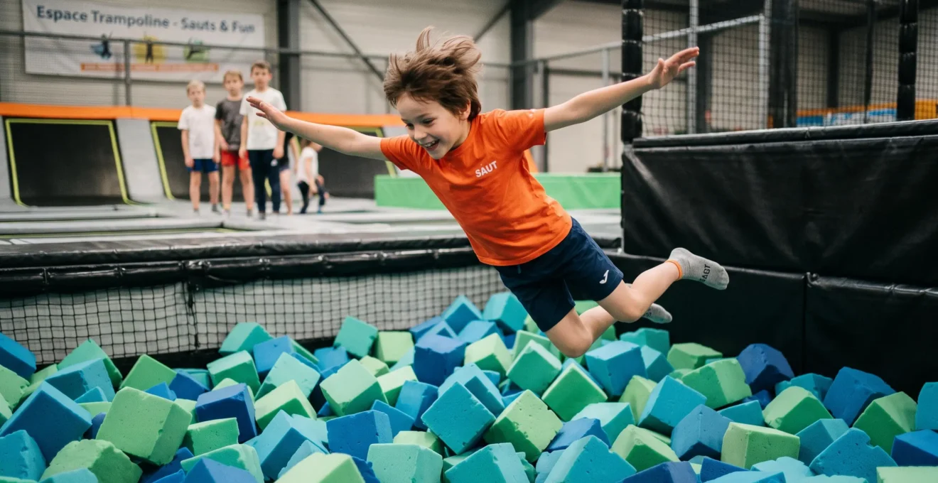 Enfant sautant dans une fosse à mousse colorée à l'intérieur d'un trampoline park