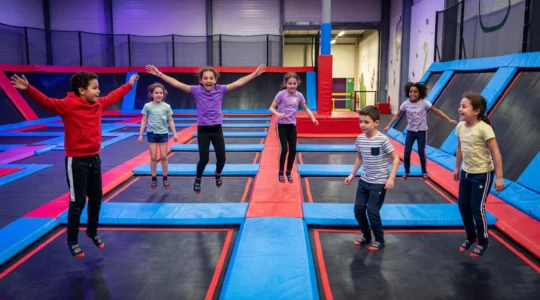Groupe d'enfants sautant activement sur des trampolines interconnectés dans une zone privatisée d'un trampoline park indoor